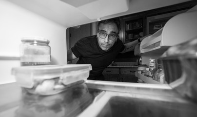 Man staying at home looking in an empty fridge for something to eat while in quarantine self isolation