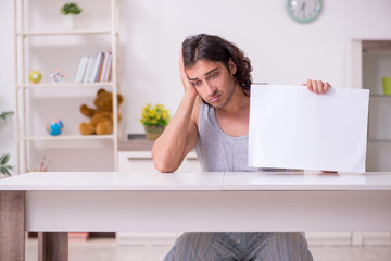Young man holding blank paper at home