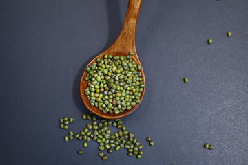 Top view of mung beans or green beans in a wooden spoon isolated on black background.  Food and health concept