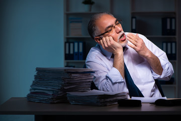 Old male employee working late in the office