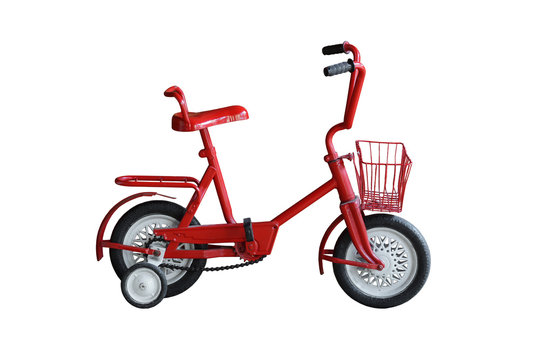 An old style bicycle for kid in red color with training wheels on isolated background