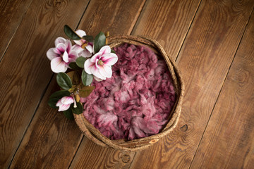 Newborn photography digital background prop. wicker basket with pink fur and flowers on a wooden background.	
