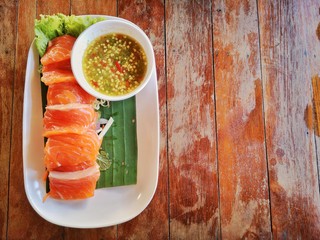 Fresh salmon placed on a white plate With wood grain background.