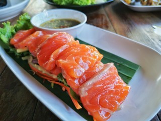 Fresh salmon placed on a white plate With wood grain background.