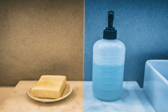 Soap Bar Versus Liquid Hand Soap Bottle Comparison Of Hand Washing Products On Home Bathroom Vanity. Yellow And Blue Color Boxes To Compare.