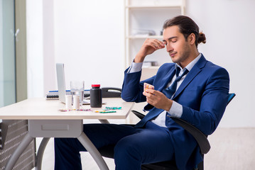 Young male employee and a lot of pills on the desk