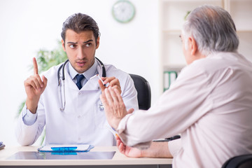 Young male doctor and old patient in antismoking concept