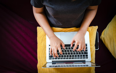 Young woman working on laptop computer while sitting on the red sofa in living room at home, working from home concept.business concept background.