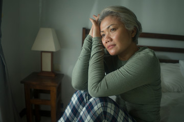 mature lady crisis - middle aged woman with grey hair sad and depressed in bed feeling frustrated and lonely thinking about aging lonely suffering depression