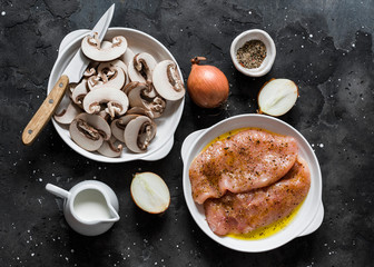 Ingredients for cooking fried chicken fillet with cheesy mushrooms cream sauce on a dark background, top view. Delicious homemade lunch