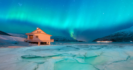 Landscape with house at night under green aurora sky - Northern lights (Aurora borealis) in the sky  - Tromso, Norway "Elements of this image furnished by NASA "