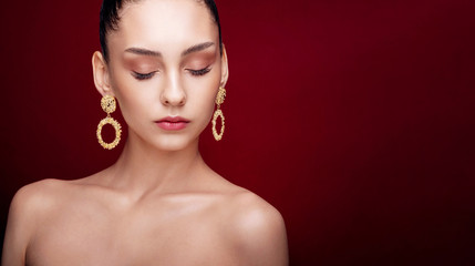 close-up beauty portrait fashion model, clean skin, red background, gold earrings, hairstyle high bun, art creative fashion photography,  copy space place for text