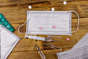 Concept of a prevention and treatment coronavirus. Medical masks, pills, syringe, ampoules on a...