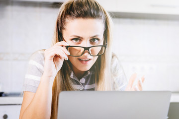 Young woman in glasses near a laptop.