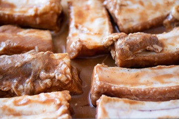 Raw marinaded juicy pork ribs ready for cooking. Meat processing picture. Food photography close up background