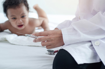 Doctor holds an injection syringe for baby  , Dark skinned baby looking at doctors and crying, selective focus