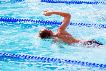 Motion blurred swimmers in a freestyle race, focus on shoulder and water drops