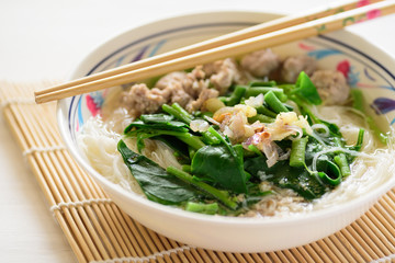 Rice noodles soup with pork meatball and vegetables in a bowl and chopsticks ready to eating, homemade Asian food