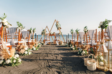 Triangular wedding arch by the sea ready for the ceremony. Wedding ceremony setup on black sand beach
