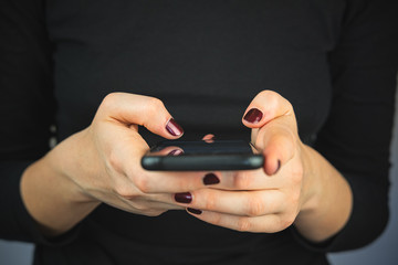 Texting on the phone, using smartphone. Female hands with a smartphone typing text and scrolling, close-up view