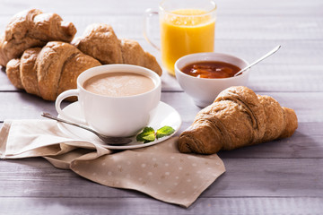 breakfast with fresh croissants and coffee on wooden table