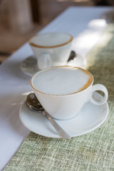 Two white cups of Cappuccino coffee with shaped milk
