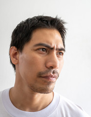 Fototapeta premium Portrait of a handsome Asian man in masculine look isolated on a white background. A serious and thoughtful adult man looks away from the camera. Close up, head shot face of the bearded male model.