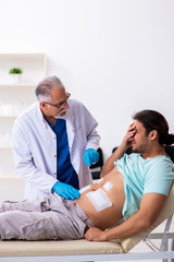 Injured young man visiting experienced male doctor