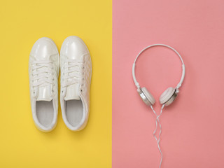 White headphones and white sneakers on a pink and yellow background.