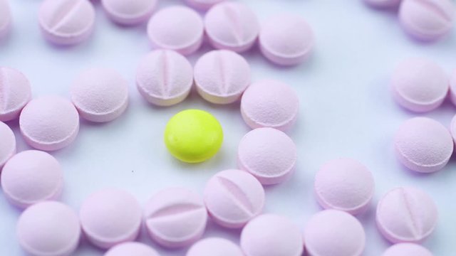 Pink pills neatly folded on a white table and rotate close up