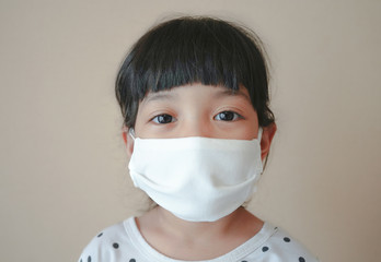 Asian kid use medical mask or surgical mask to protect her from virus, sickness, Covit-19 and coronavirus infection.