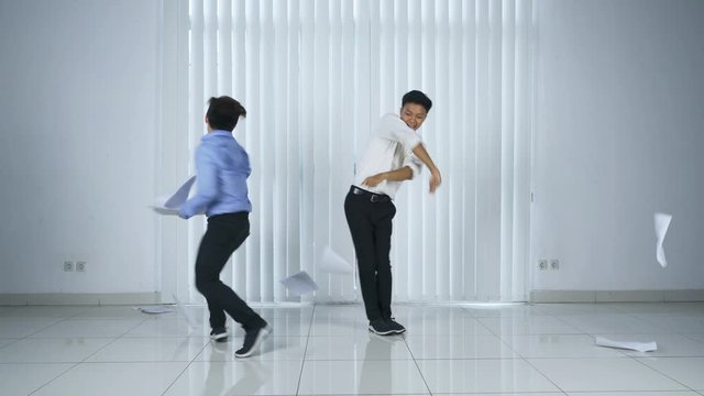 Two businessman dances and throws paperwork