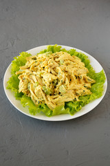 Homemade Coronation Chicken Salad on a white plate on a gray surface, low angle view. Close-up.