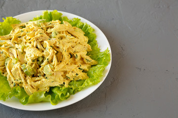 Homemade Coronation Chicken Salad on a white plate on a gray surface, low angle view. Copy space.