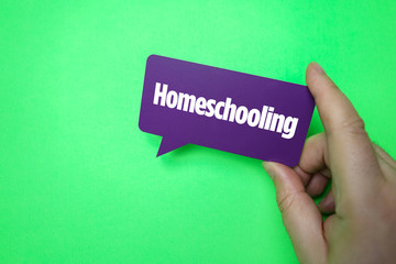 Hand holding speech bubble with Homeschooling.