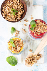 Vegan blue spirulina chia puddings with jam and granola in glass jars on a light blue table. Concept of healthy eating, dieting, fitness menu. Various layered dessert for breakfast. Top view.