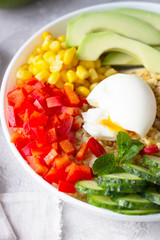 Buddha bowl with soft boiled egg, avocado, grilled chicken, cucumber, bell pepper, corn and bulgur. Concept for clean and balanced healthy food. Top view.