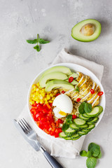 Buddha bowl with soft boiled egg, avocado, grilled chicken, cucumber, bell pepper, corn and bulgur. Concept for clean and balanced healthy food. Top view.