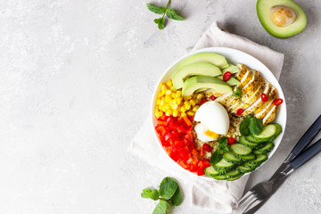 Buddha bowl with soft boiled egg, avocado, grilled chicken, cucumber, bell pepper, corn and bulgur. Concept for clean and balanced healthy food. Top view.