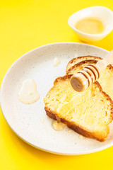 Sandwich with honey on a plate. Yellow paper background. Idea for breakfast or snack. Top view.
