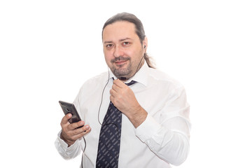 A man in a white shirt and tie speaks on a cell phone with a wired microphone and earphone