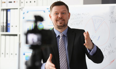 Male in suit and tie show stats graph pad making promo videoblog or photo in office camcorder to tripod portrait. Vlogger selfie solution or finance advisor management information professional concept © H_Ko