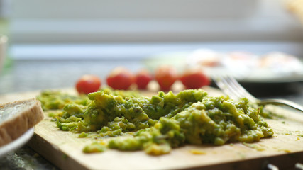 Close up of mashed avocado on a wooden board for guacamole ar bruschetta