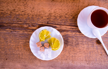 Mug of tea, plate with lime, sahora, on wooden background
