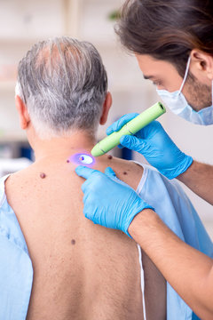 Old Man Visiting Young Male Doctor Dermatologist