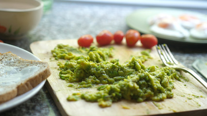 Close up of mashed avocado on a wooden board for guacamole ar bruschetta