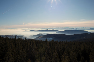 Obraz premium View over Rogla shot from the Tree Tops Walk. Beautiful view of the cloudy skyes and forest in Pohorje in Slovenia. Popular tourist attraction and viewpoint.