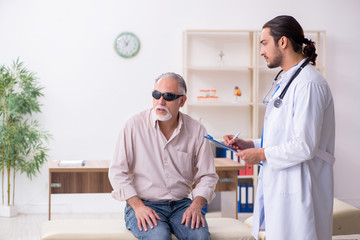 Obraz premium Old blind man visiting young male doctor