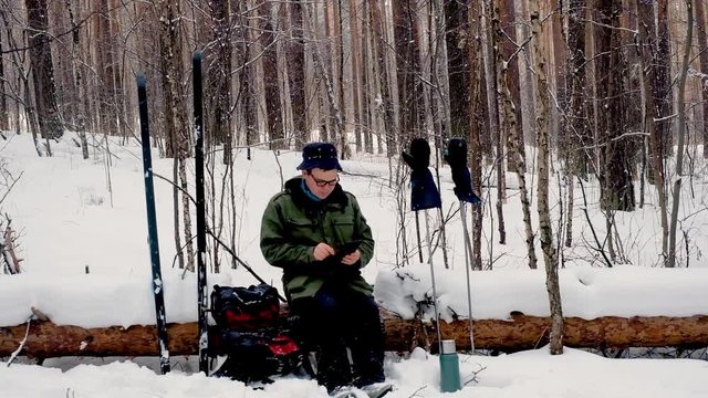 travel concept - tourist takes picture of two pairs of wide skis in village in winter day on smartphone, Russia