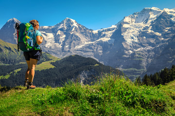 Naklejka na ściany i meble Happy hiker woman with backpack, enjoying the view, Murren, Switzerland